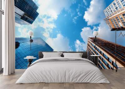 The image features a dynamic perspective of towering skyscrapers set against a bright blue sky with scattered clouds, embodying urban ambition and modern architecture. Wall mural