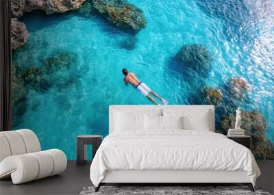 The picture captures a person snorkeling in crystal clear blue waters, surrounded by vibrant coral formations and beautiful marine life, creating an underwater adventure scene. Wall mural