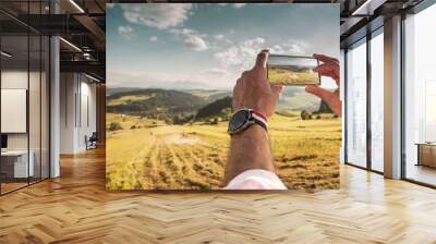 Tourist man taking photo of landscape with smartphone Wall mural