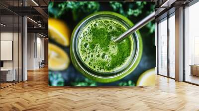 A vibrant green kale smoothie in a mason jar with a reusable metal straw, surrounded by kale leaves and lemon wedges Wall mural