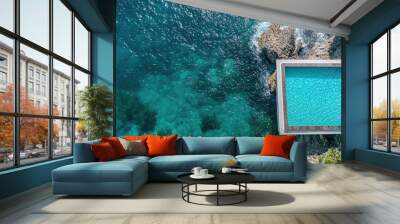 Top view of an infinity pool at a seaside resort with clear blue waters merging with the ocean. Wall mural