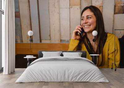 Copy space attractive young woman sitting in a table restaurant having a phone call talking with somebody with smiley face. Wall mural