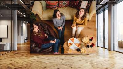 from above company of cheerful ethnic female friends eating pizza while gathering at home at weekend Wall mural