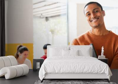 Horizontal banner or header smiling African handsome young man holding tablet and looking at camera. Group of people sitting ad desk on background. Wall mural