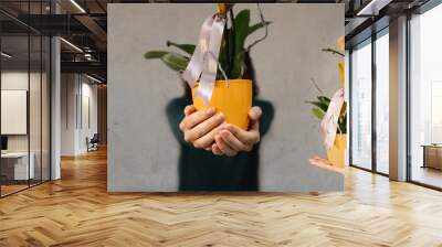 Horizontal banner standing woman in the middle offering a potted plant with two arms on the sides holding the same yellow orchid flower. Gardening, care, gift, present concept. Wall mural