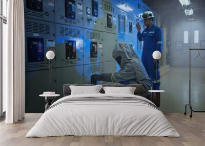 Electrical worker wearing arc flash suit protection is used to draw out a large circuit breaker. Wall mural