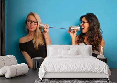 blonde and brunette women talking with tin can telephone against Wall mural