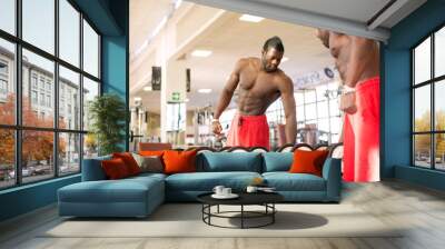 Strong black man exercising with dumbbells in the gym. Wall mural