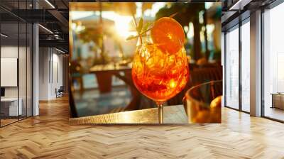 Aperol Spritz alcoholic cocktail stands on table on summer terrace in cafe against backdrop of sunset. Wall mural