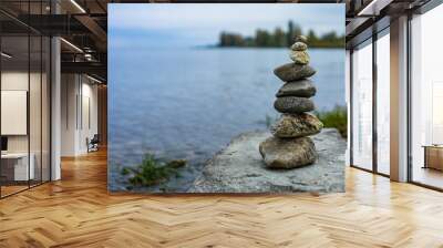 A stack of rocks on a rock by the water Wall mural