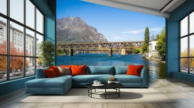 Buildings of the city of Lecco on the banks of the river Adda. Bridges and an island with mountains in the background Wall mural