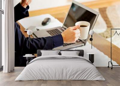 Man working on laptop and drinking coffee at home Wall mural