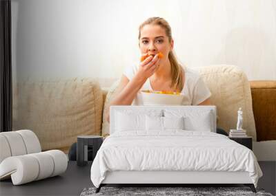 Woman eating chips and watching tv. She is stressed and she eating junk food. Wall mural