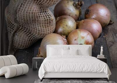 Tasty ripe onion in a jute sack. Vegetables hollowed out in the garden on an old wooden table. Wall mural