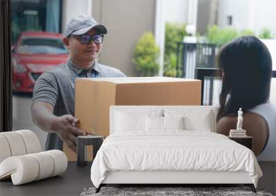 delivery man holding a large box to send to customers in front of the house Wall mural