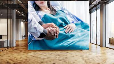 Male doctor holding female patient hand on the hospital bed. Wall mural