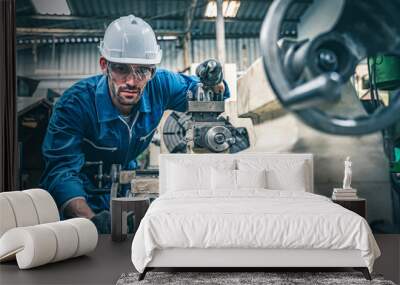 Male worker in blue jumpsuit and white hardhat operating lathe machine.  Wall mural