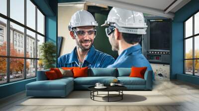 Two male workers in blue jumpsuits and hard hats discussing work in the factory. Wall mural