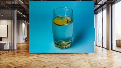 Glass of water whit the lime on blue marine background Wall mural