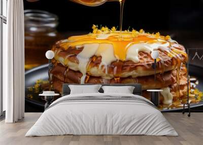 A chef's hand drizzling honey over a stack of fluffy pancakes. Wall mural