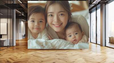 Portrait of enjoy happy love family asian mother playing with adorable little asian baby and sister girl, newborn, infant.Mom touching care with cute son in a white bedroom.Love of family concept Wall mural