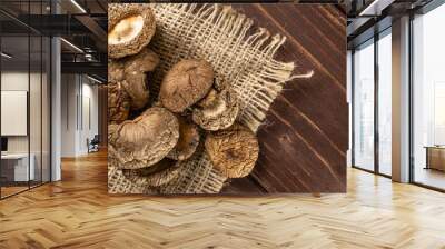 Lot of whole dry mushroom shiitake on jute cloth flatlay on brown wood Wall mural