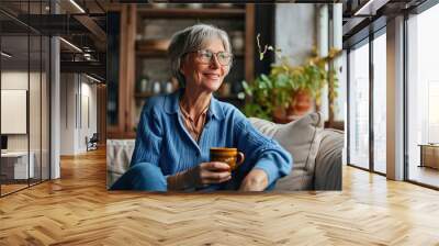 Smiling mature elder 60s woman sitting relaxing with cup of tea, coffee. Senior mid age stylish look woman with eyeglasses portrait with cup looking away at modern, Generative AI  Wall mural