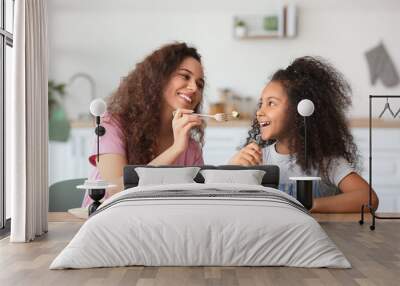 African-American little girl with her mother eating fresh salad in kitchen Wall mural