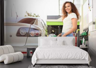 African-American woman filling up car tank at gas station Wall mural