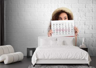 African-American woman holding calendar with marked days of menstruation on white background Wall mural