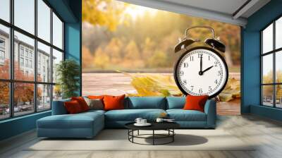 Alarm clock and autumn leaves on table outdoors Wall mural