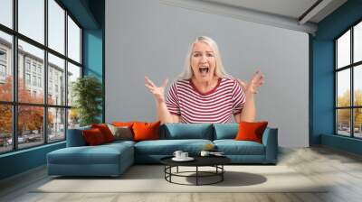 Angry mature woman on grey background Wall mural