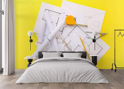 Architect's supplies with eyeglasses and house plans on yellow background Wall mural