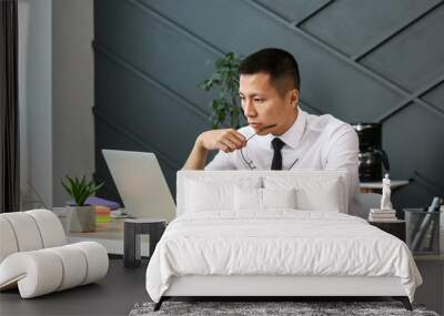 Asian businessman working on laptop in office Wall mural