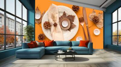 Autumn table setting with dried leaves, cones and burning candles on orange background Wall mural