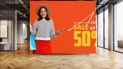 Banner for autumn sale with with young woman holding mobile phone and shopping bags Wall mural