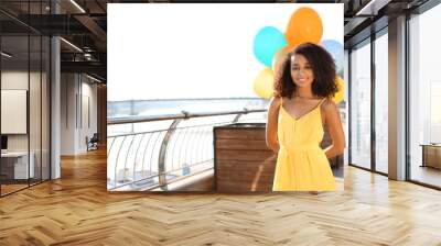 Beautiful African-American woman with balloons outdoors Wall mural