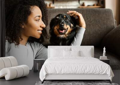 Beautiful African-American woman with cute dog at home Wall mural