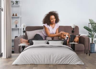 Beautiful African-American woman with cute dog at home Wall mural