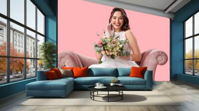 Beautiful bride with wedding bouquet in armchair on pink background Wall mural