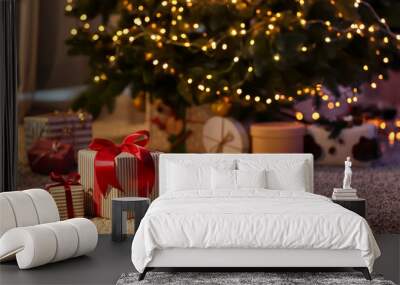 Beautiful Christmas gift boxes on floor near fir tree in room Wall mural