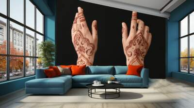 Beautiful female hands with henna tattoo on dark background Wall mural