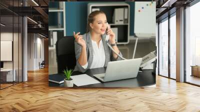 Beautiful female secretary talking on telephone in office Wall mural