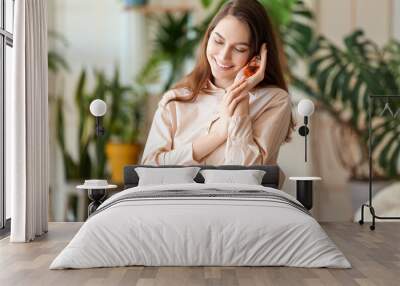 Beautiful happy woman holding bottle of natural essential oil in room Wall mural