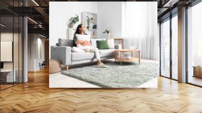 Beautiful happy young woman relaxing on sofa in living room Wall mural