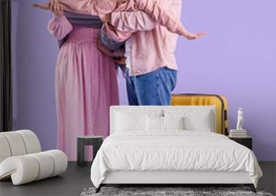 Beautiful Muslim family with suitcase and backpack on lilac background. Travel concept Wall mural