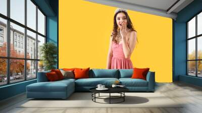 Beautiful surprised young woman in stylish prom dress and tiara on yellow background Wall mural