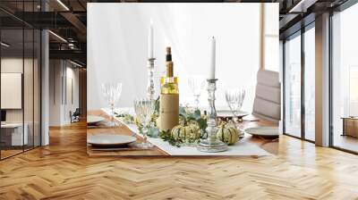 Beautiful table serving with autumn decor, bottles of wine and candles in light room Wall mural