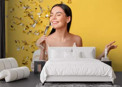 Beautiful woman drinking champagne and falling confetti on color background Wall mural