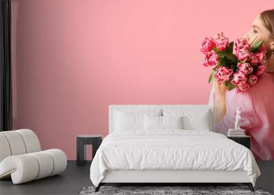 Beautiful woman holding bouquet of flowers on pink background with space for text. International Women's Day Wall mural